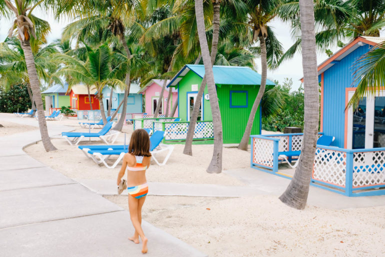 daughter walking in bathing suit by colorful bungalows