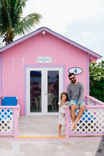 dad and daughter in front of pink bungalow