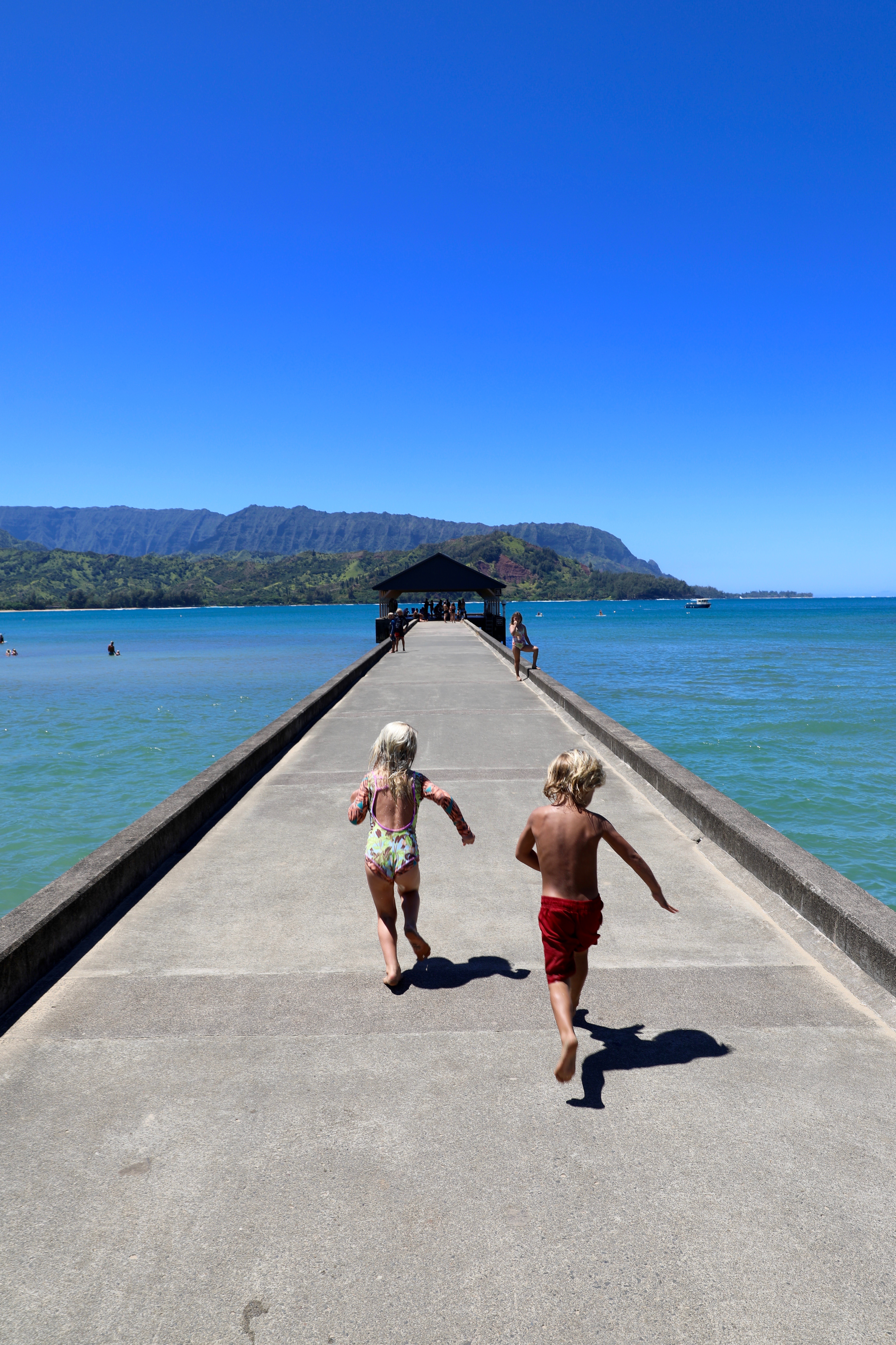 kids running on pier surrounded by water